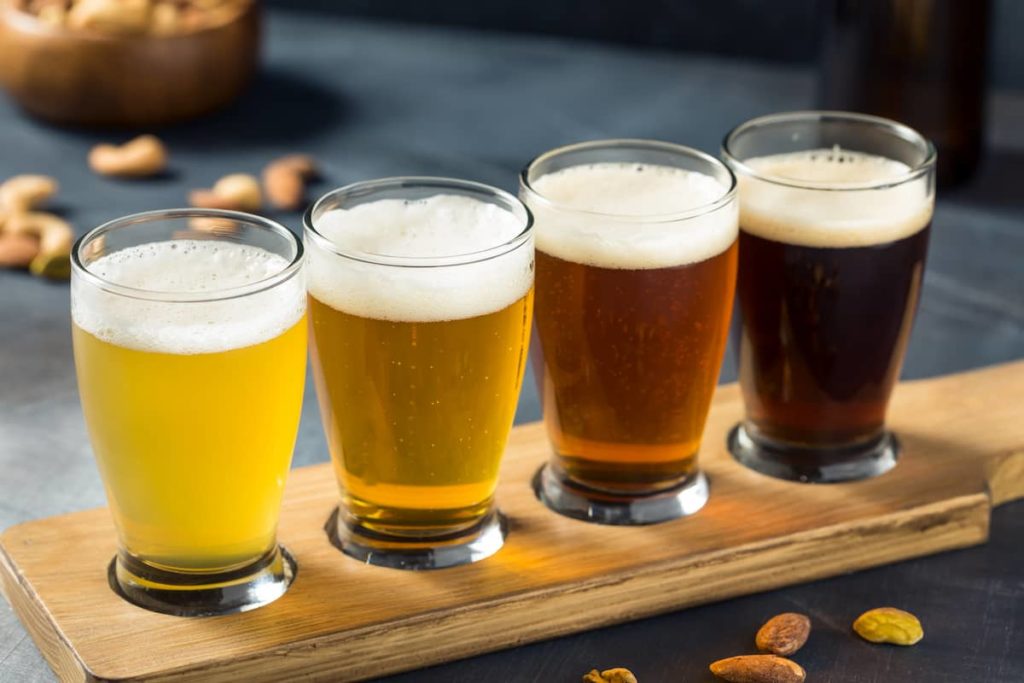 Varios tipos de cerveza servidos en vasos sobre un beer flight